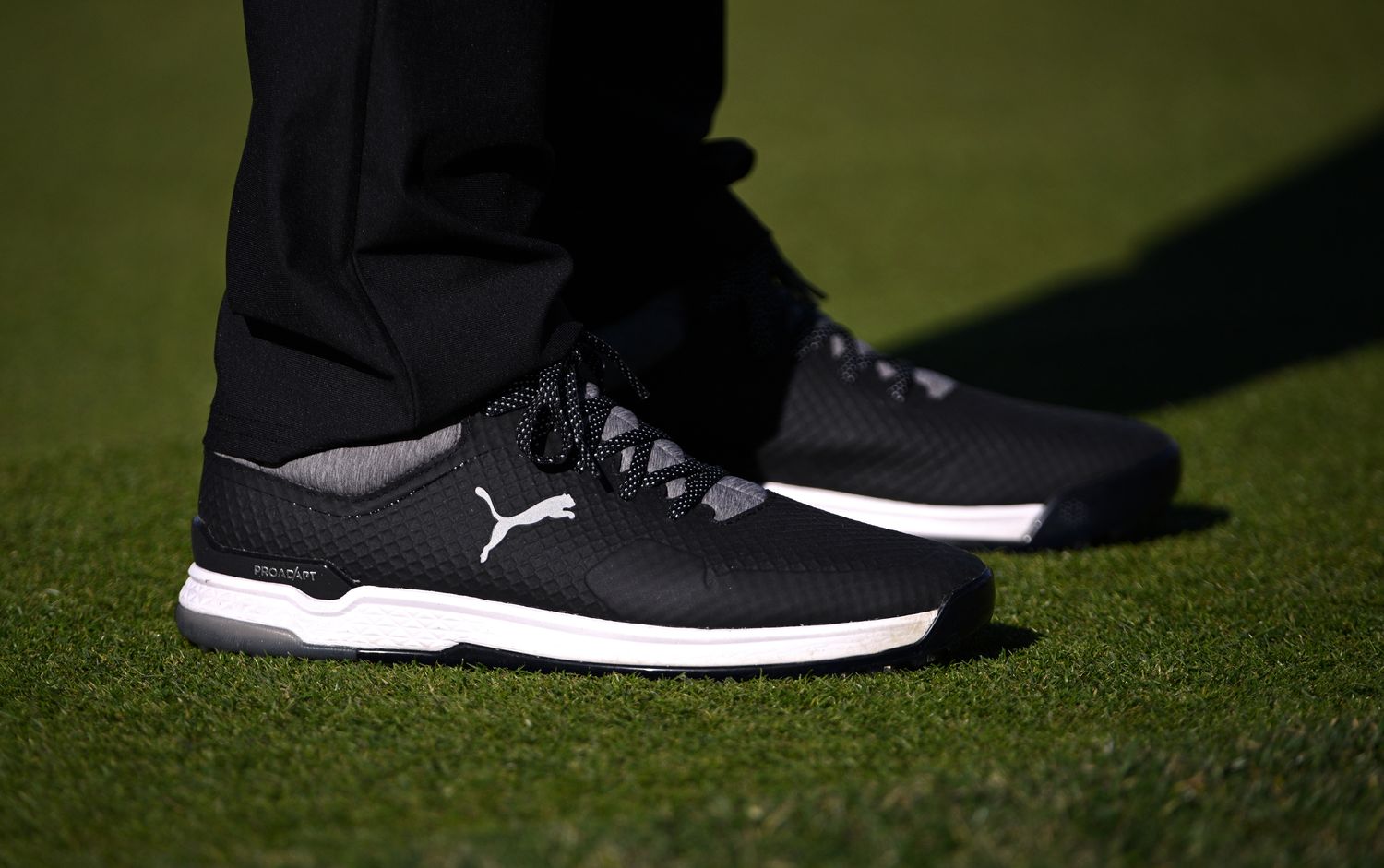 View of Rickie Fowler's black and white PUMA golf shoes.